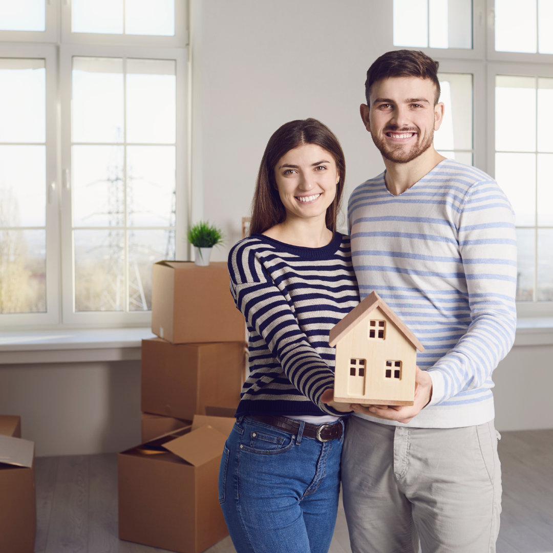 Happy couple holding a miniature house model symbolizing dream home ownership with the best real estate developers in Hyderabad
